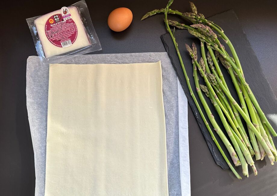 Essential ingredients for this recipe include puff pastry, fresh asparagus, Murcia al Vino cheese, and olive oil